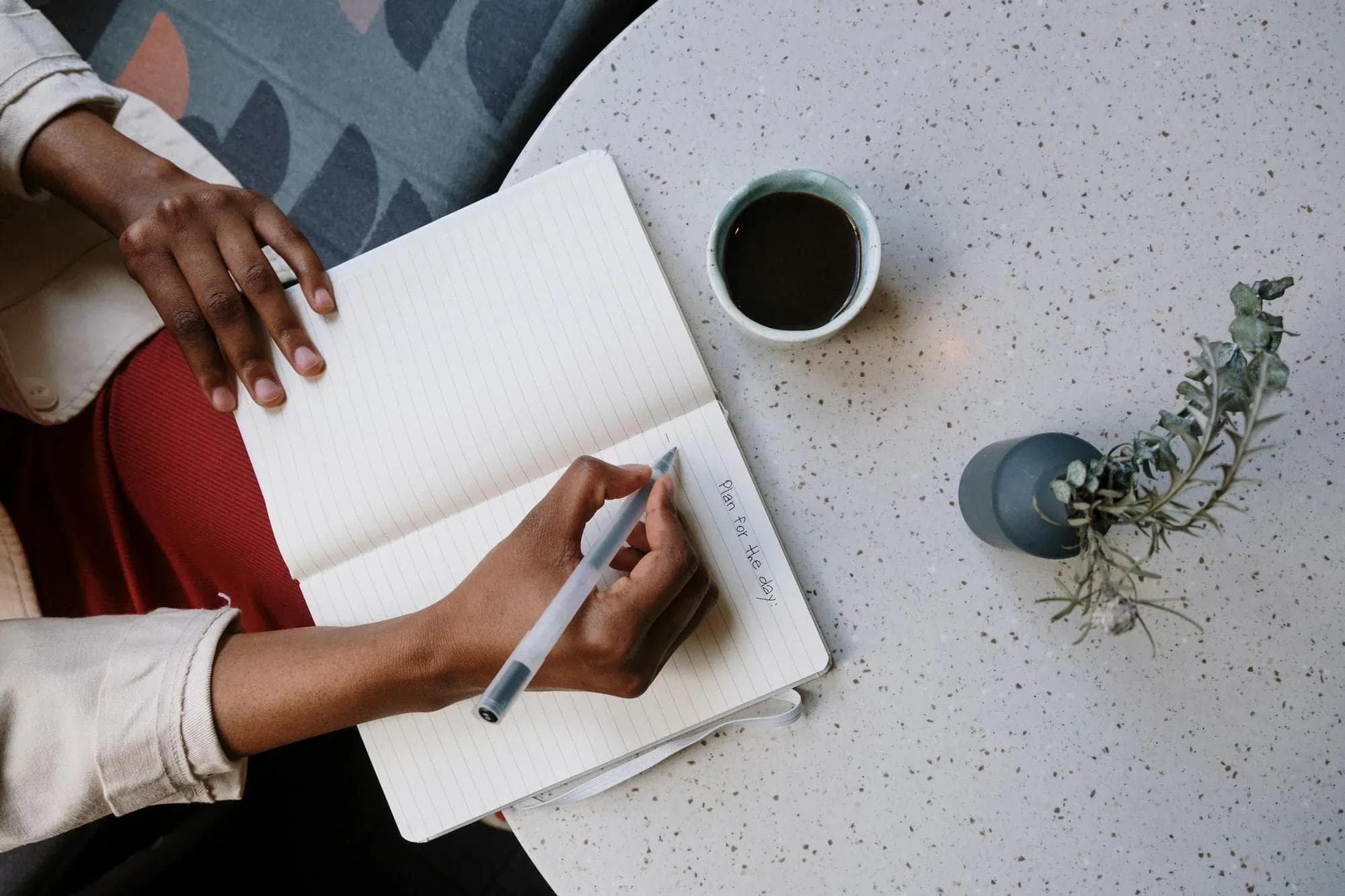 Writing daily plan in notebook with coffee